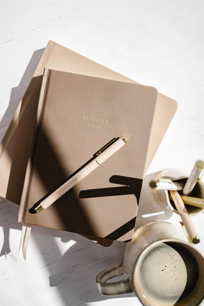 Elegant beige planner with pen and coffee, perfect for organizing daily tasks in style.