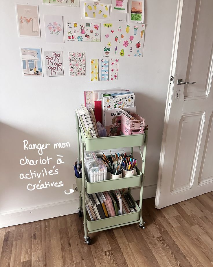 Green craft cart with art supplies and colorful wall prints in a creative workspace.
