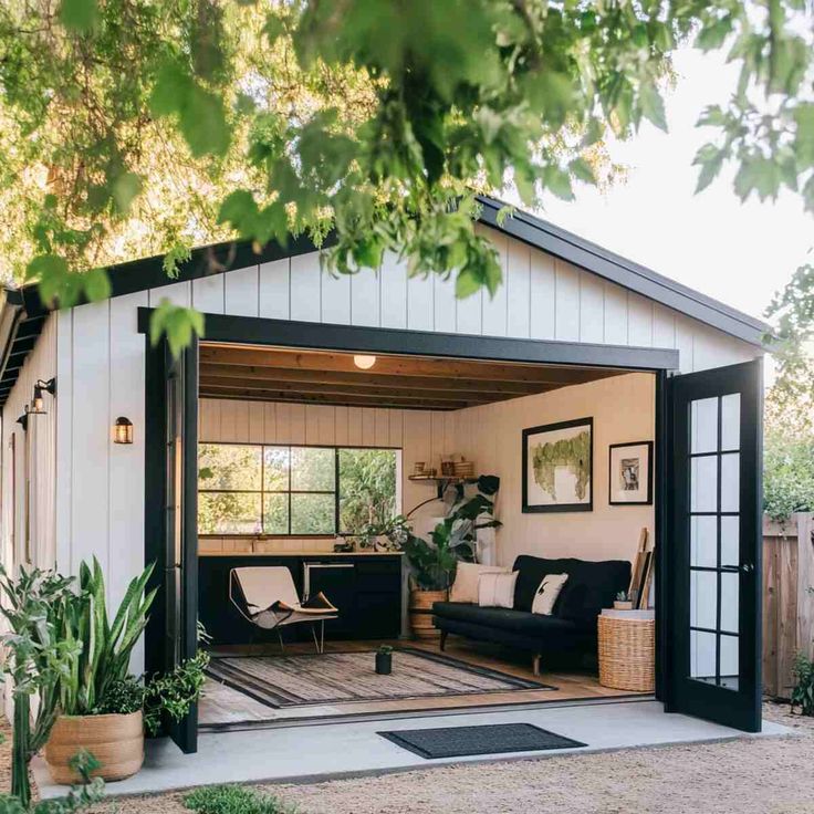 Looking for creative Garage Conversion Ideas_ Discover 23 practical ways to transform your garage into a home office gym guest room or more_ Maximize your space and add value to your home today Cozy modern shed with open doors, inviting interior, plants, and seating, surrounded by greenery in a backyard setting. | Sky Rye Design Cozy modern shed with open doors, inviting interior, plants, and seating, surrounded by greenery in a backyard setting.