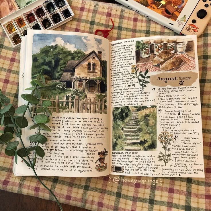 Artistic journal spread with watercolor sketches of a cottage and plants, surrounded by art supplies on a plaid surface.