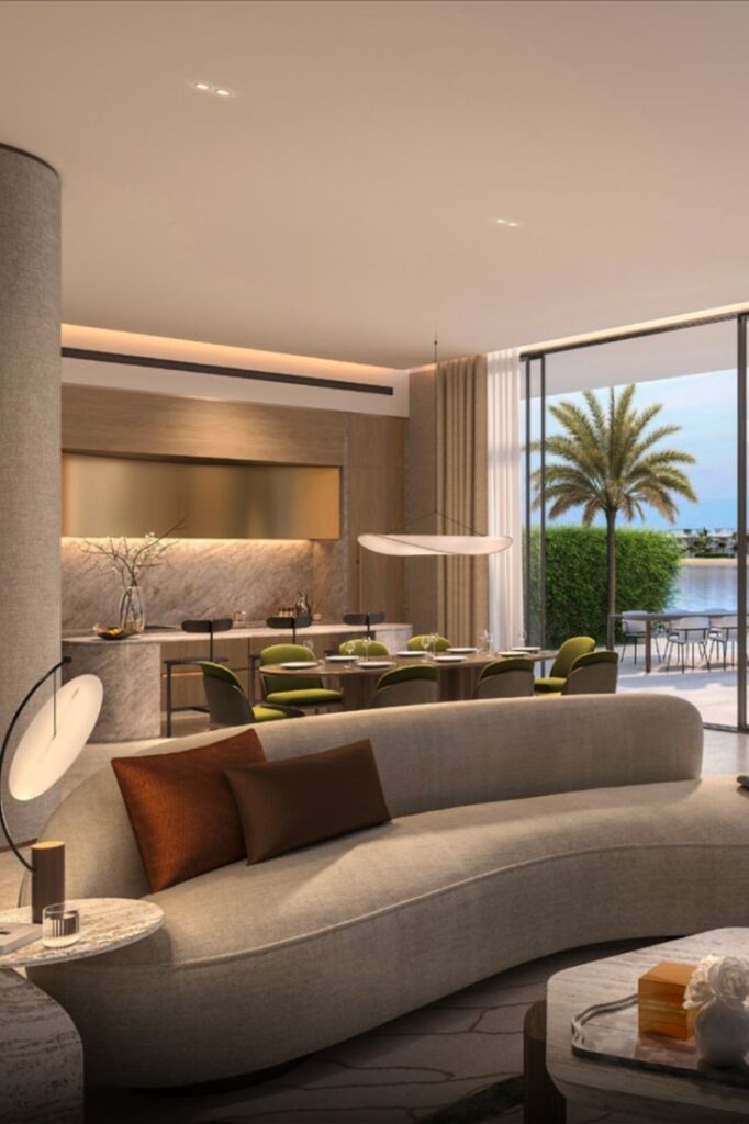 Luxurious modern living room with elegant furniture and floor-to-ceiling windows overlooking a palm tree and water view.