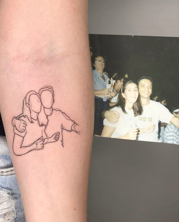 Tattoo outline on arm mirrors a photo of a smiling couple embracing, capturing a cherished memory.