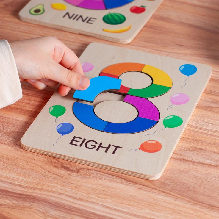 Child assembling a colorful wooden number 8 puzzle on a table, educational toy with balloon design.