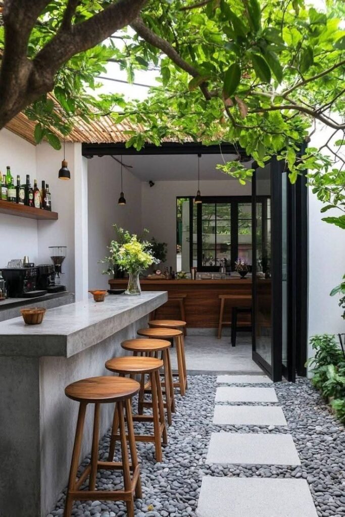 Modern outdoor bar with wooden stools, concrete counter, and lush greenery. Inviting space for relaxation and dining.