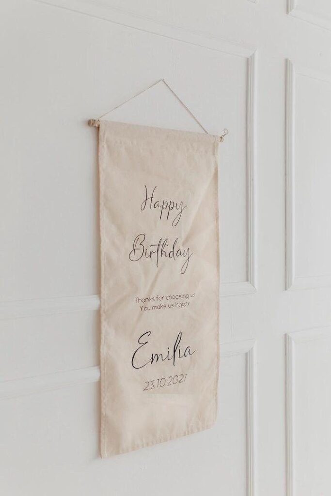 Elegant birthday banner hanging on a white door, personalized with Emilia's name and date, October 23, 2021.