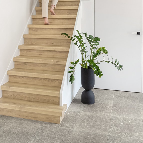 Modern wooden staircase with a potted plant beside it in a minimalist home interior.