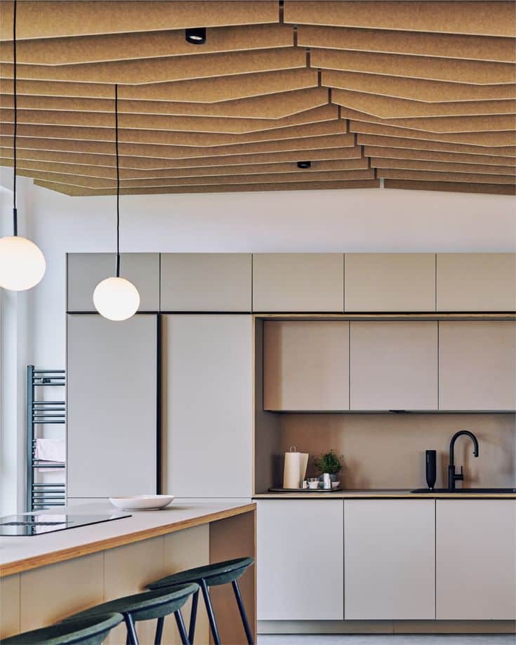 Modern kitchen with wooden acoustic ceiling, pendant lights, minimalist cabinets, and bar stools.