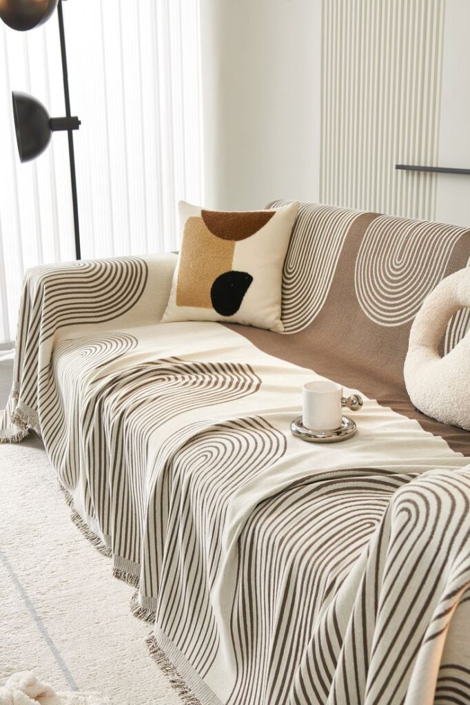 Modern living room with geometric patterned throw and cushion on beige sofa, featuring a cozy coffee setup.