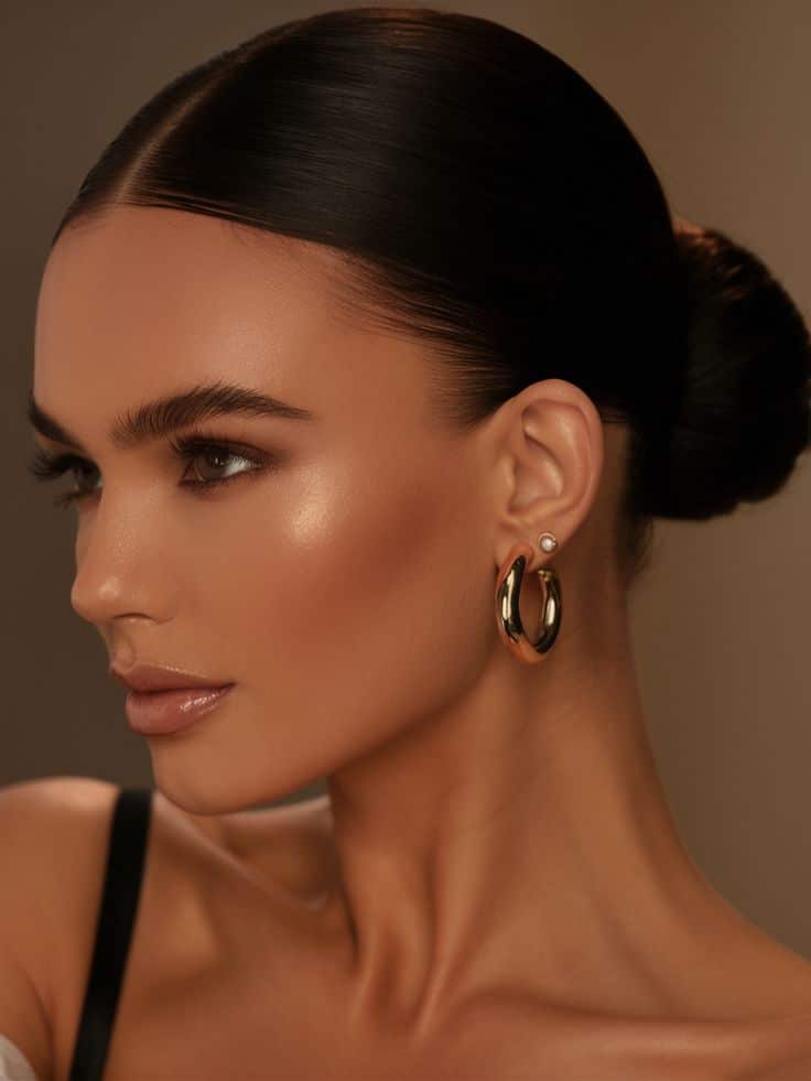 Spring Hairstyles Ideas 2025 22 Trendy Cute Looks for Short Long Curly Hair Close-up of a woman with sleek hair in a bun, wearing gold hoop earrings, showcasing elegant makeup and glowing skin. | Sky Rye Design Close-up of a woman with sleek hair in a bun, wearing gold hoop earrings, showcasing elegant makeup and glowing skin.