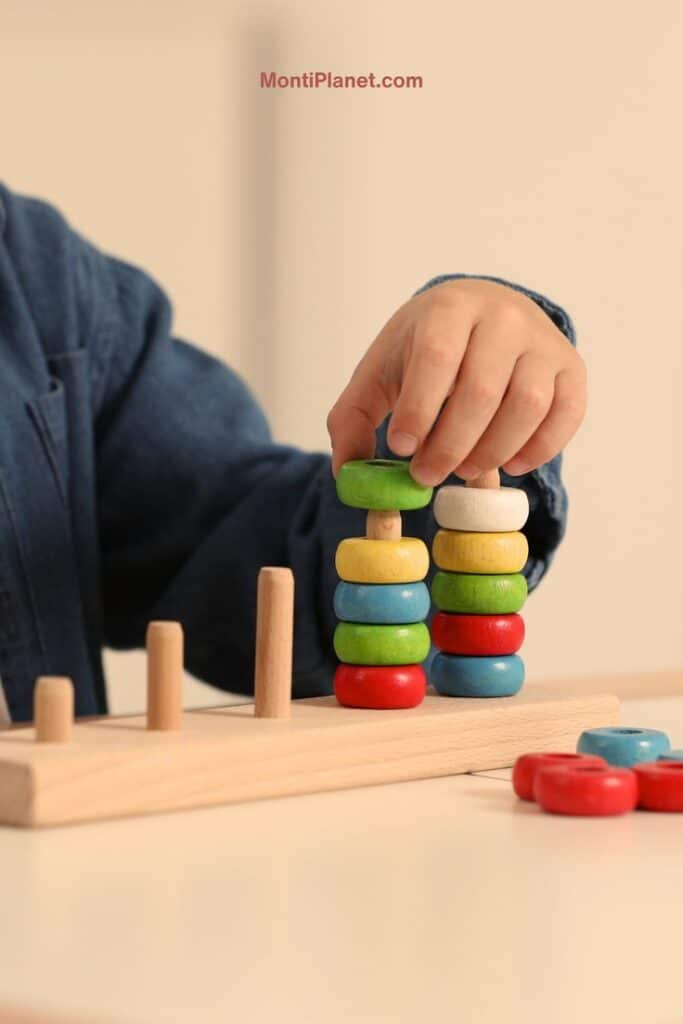 Child stacking colorful wooden rings on peg toy for motor skills development.
