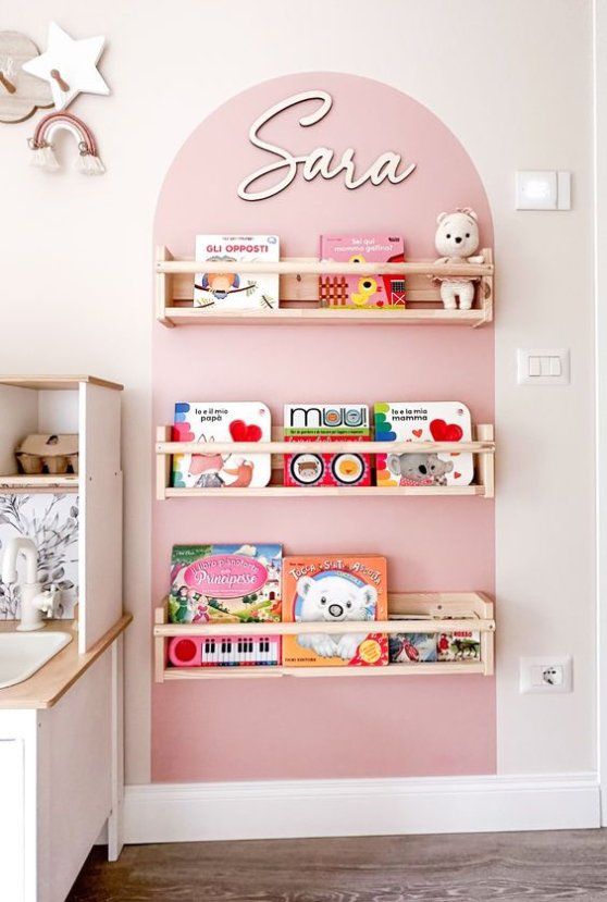 Children's book wall shelves with toys and decor in a pastel-themed room.