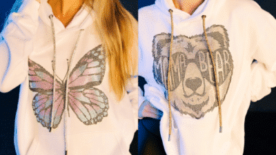 Two white hoodies with sequin designs: one features a colorful butterfly, the other a bear with mama bear text.