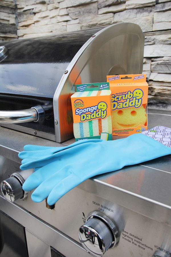 Cleaning supplies on a grill: Scrub Daddy sponges and gloves ready for outdoor cleaning tasks.