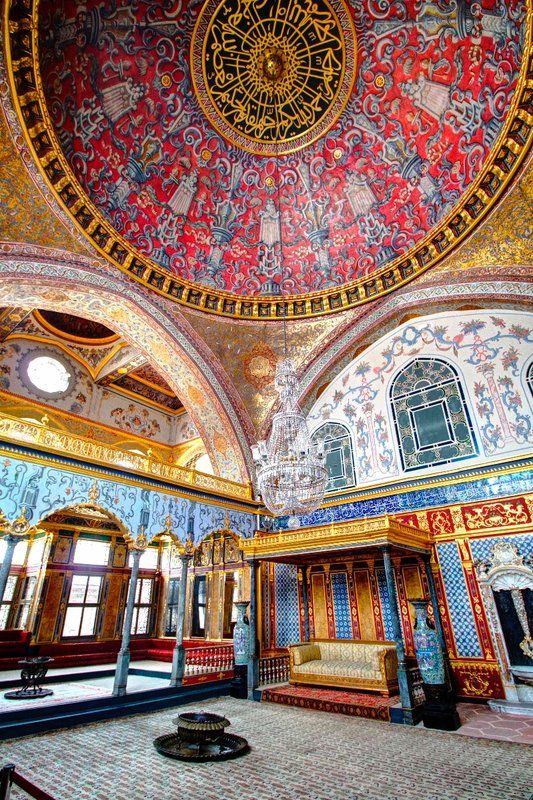 Ornate palace interior with colorful domed ceiling, intricate patterns, chandeliers, and elegant furnishings.
