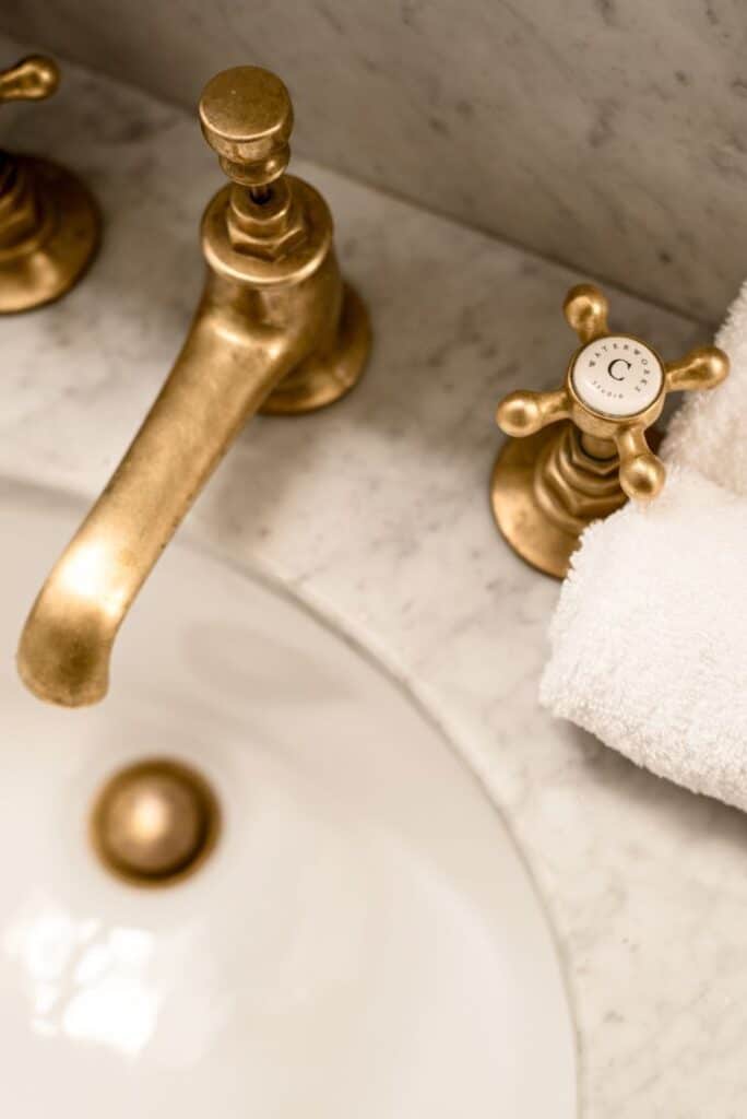 Luxurious gold bathroom faucet with white hand towel on a marble counter, showcasing classic bathroom decor style.