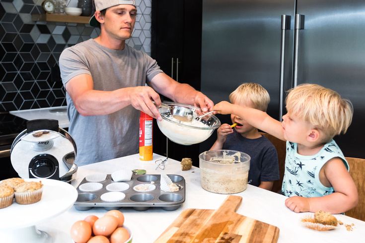 Father and kids enjoying baking muffins together in a modern kitchen.