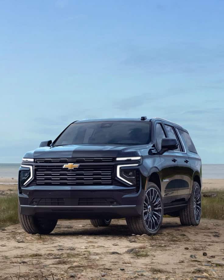 Black SUV parked on a sandy beach with a clear blue sky background.