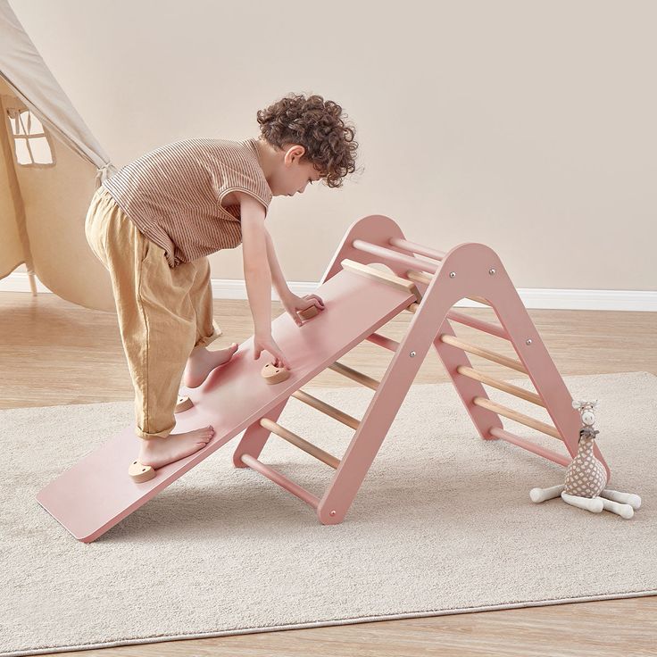 Child climbing pink indoor play gym for toddlers in a playroom, promoting physical activity and fun.