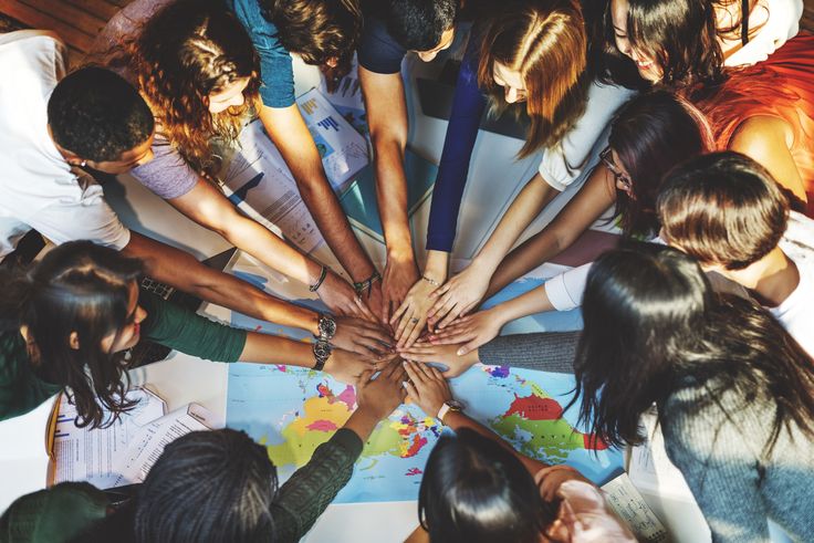 Diverse group of people uniting hands over a world map, symbolizing global teamwork and collaboration.