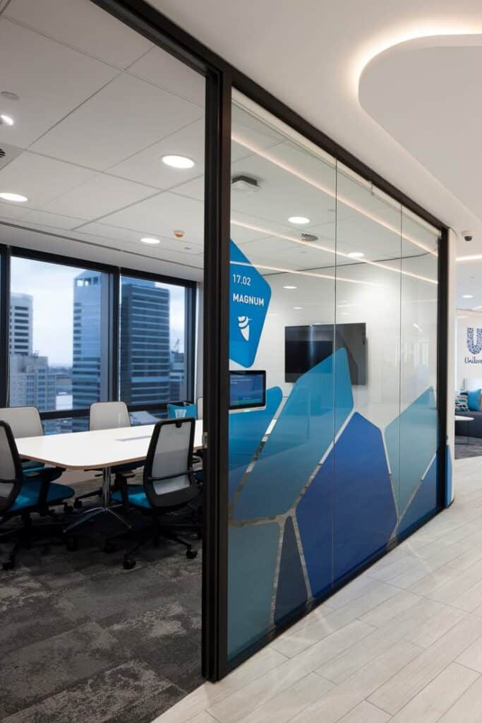 Unilever Sydney CBD office - ODCM _ Modern office conference room with glass walls, blue accents, and city view. | Sky Rye Design Modern office conference room with glass walls, blue accents, and city view.
