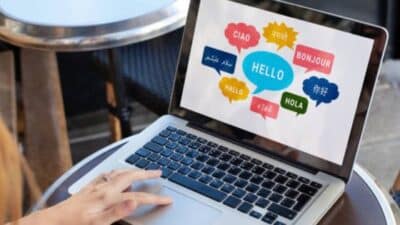 Person using a laptop showing Hello in different languages, illustrating multilingual communication.