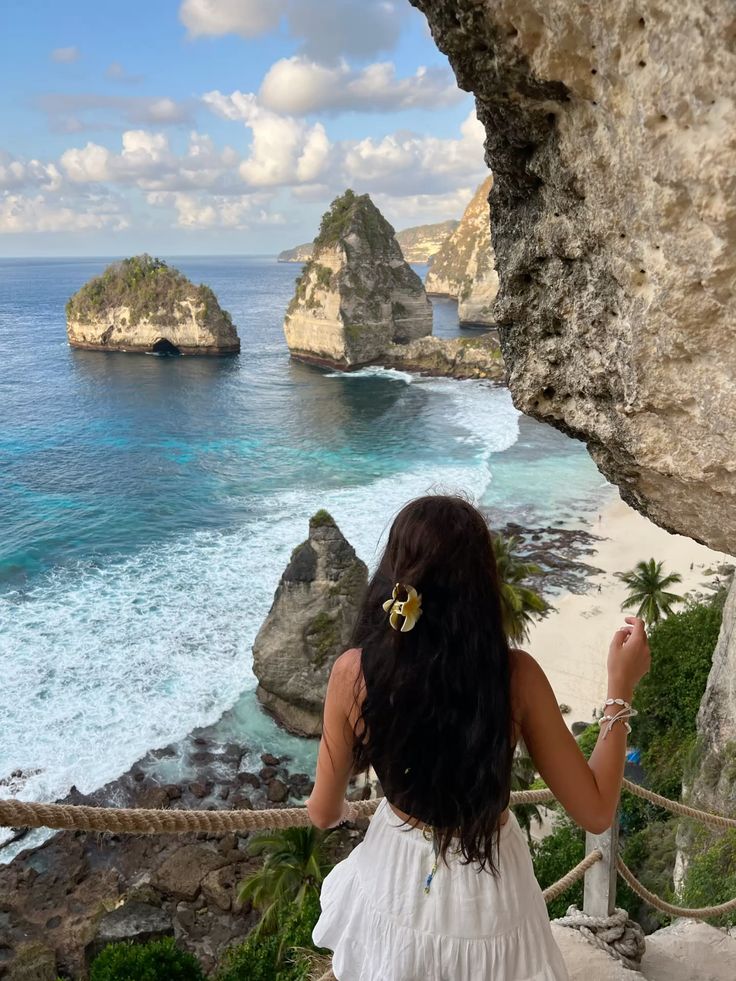 Vacation vibe Woman in white dress overlooks stunning coastal cliffs and turquoise ocean at a tropical destination. | Sky Rye Design Woman in white dress overlooks stunning coastal cliffs and turquoise ocean at a tropical destination.