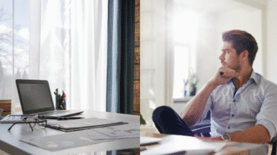 Professional pondering at desk with open laptop by window, contemplating ideas.