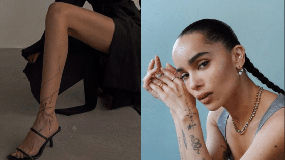 Stylish woman with long braids and tattoos poses in elegant attire, showcasing jewelry and fashion accessories.