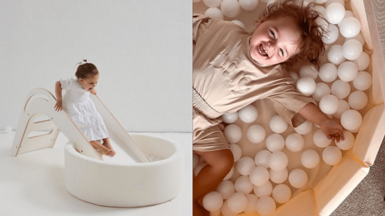 Child sliding into a soft ball pit, enjoying playful moments, and smiling happily amidst white play balls.