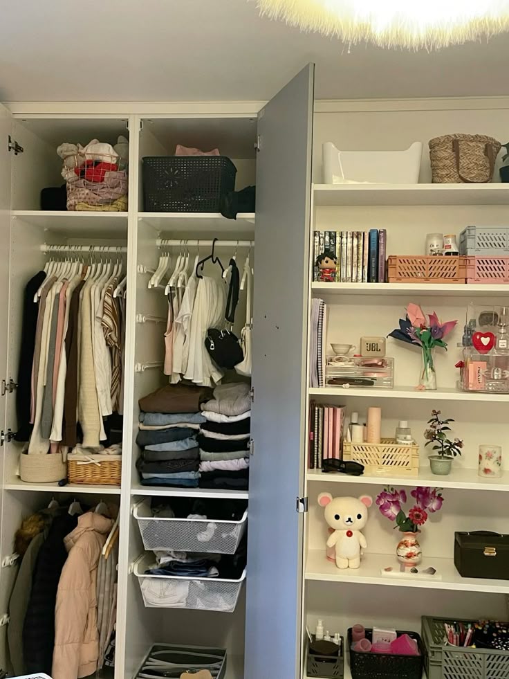 Neatly organized closet with hanging clothes, folded items, and decorative shelves featuring books, flowers, and a cute bear.