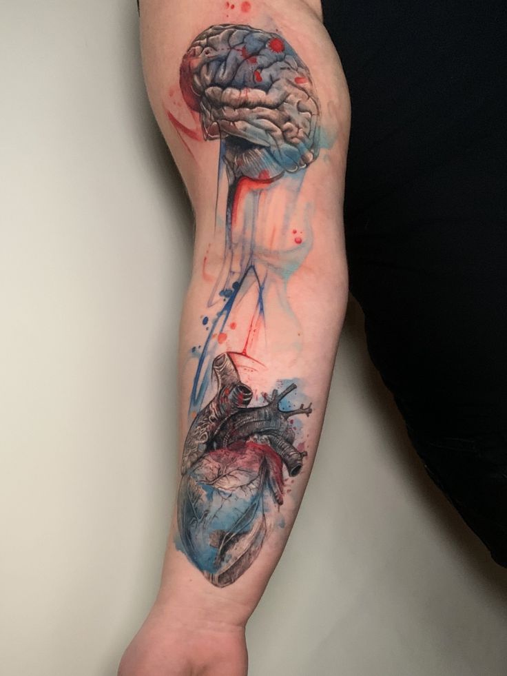 Forearm tattoo featuring a watercolor-inspired design of a brain and heart interconnected with vibrant colors.