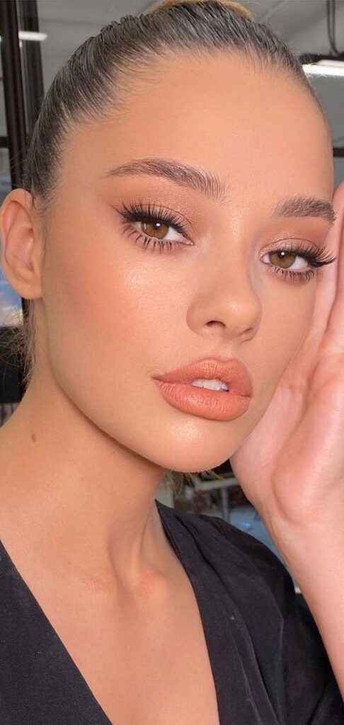 Close-up portrait of a woman with natural makeup, full lips, and sleek hairstyle, exuding elegance and confidence.