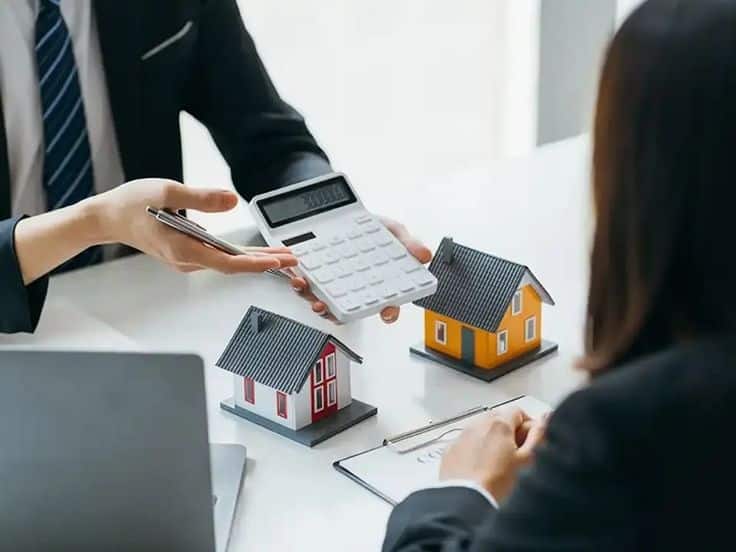 What Does a Commercial Property Management Company Actually Do_ Real estate discussion with a calculator and house models on a table, symbolizing mortgage planning. | Sky Rye Design Real estate discussion with a calculator and house models on a table, symbolizing mortgage planning.