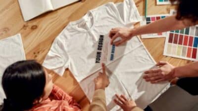 People discussing custom t-shirt design with color samples on a wooden table.