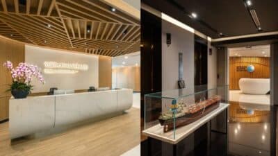 Modern office reception area with a wooden ceiling, marble desk, and a ship model display in a sleek hallway.