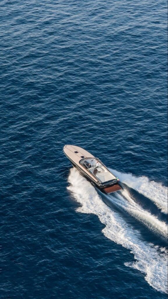 Aerial view of a luxury yacht cruising on the open ocean, leaving a white wake trail behind.