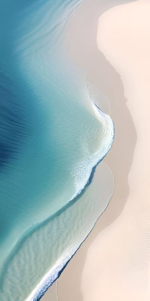 Aerial view of a pristine beach with turquoise water meeting soft white sand, creating a serene coastal landscape.