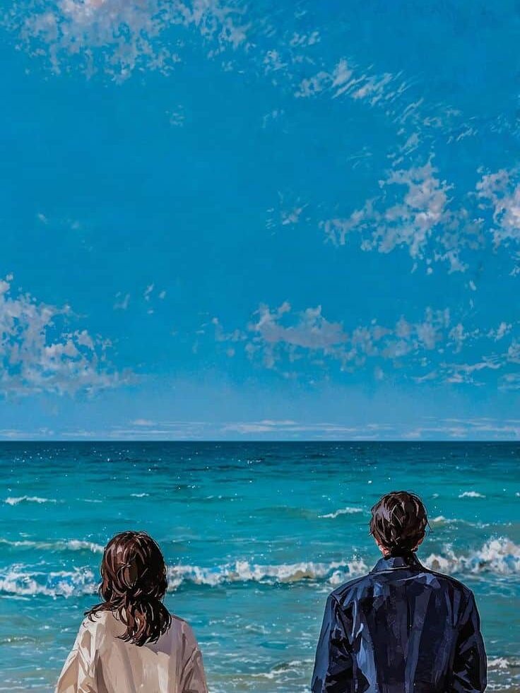 Two people standing on a beach, gazing at the ocean under a bright blue sky with scattered clouds.