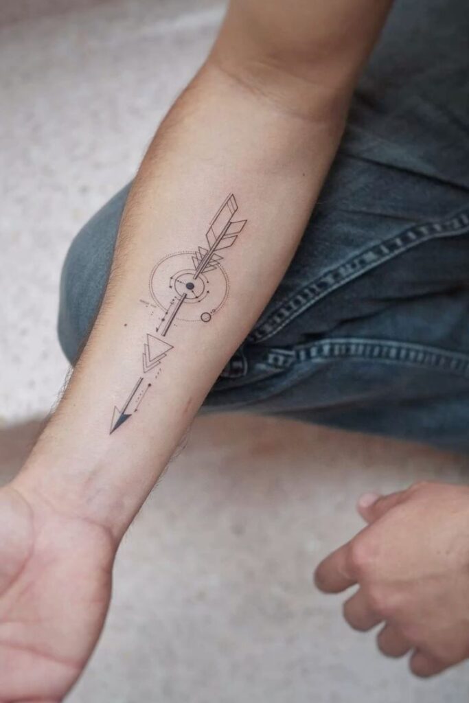 Geometric arrow tattoo on forearm, featuring circles and lines. Minimalist design on skin in casual setting.