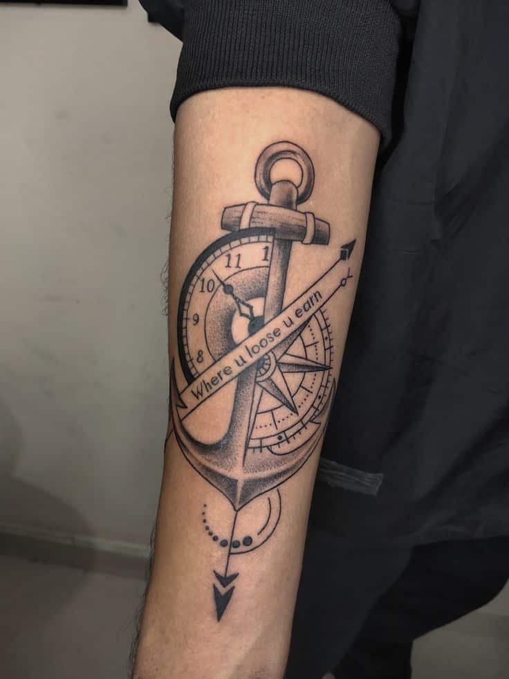 Anchor and compass tattoo on forearm with the phrase Where u loose u earn.