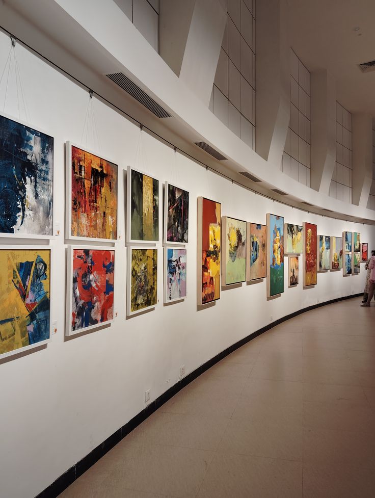 Contemporary art gallery with colorful abstract paintings on curved wall display.
