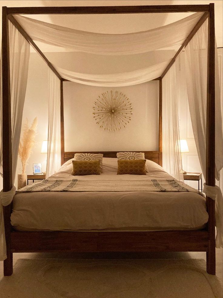 Elegant four-poster bed with sheer drapes, golden cushions, and ambient lighting for a cozy bedroom atmosphere.