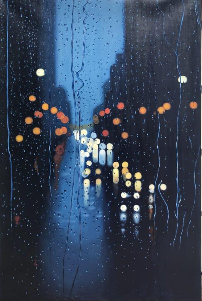 Blurred city streetlights seen through a rainy window at night, creating a moody and atmospheric scene.