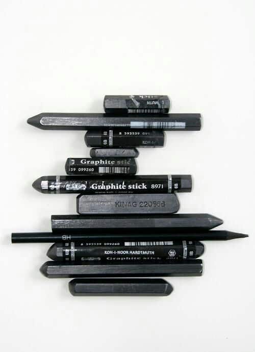Assorted graphite sticks and pencils on a white background for drawing and sketching artists.
