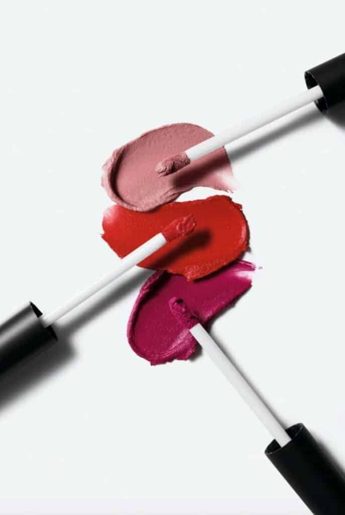 Lip gloss swatches in pink, red, and magenta shades with applicators on a white background.