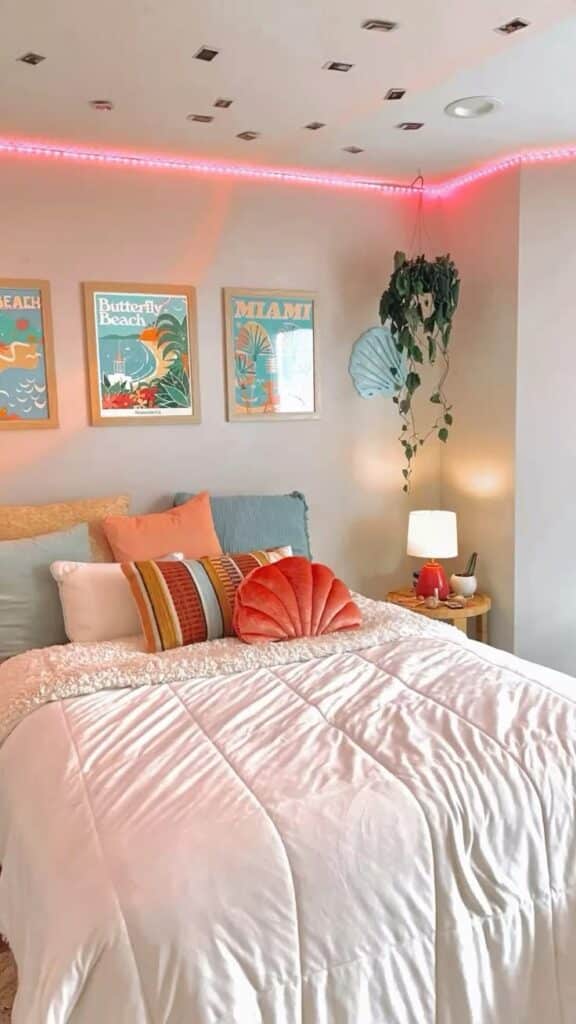 Cozy bedroom with colorful pillows, beach-themed art, plants, and soft lighting creating a relaxing ambiance.