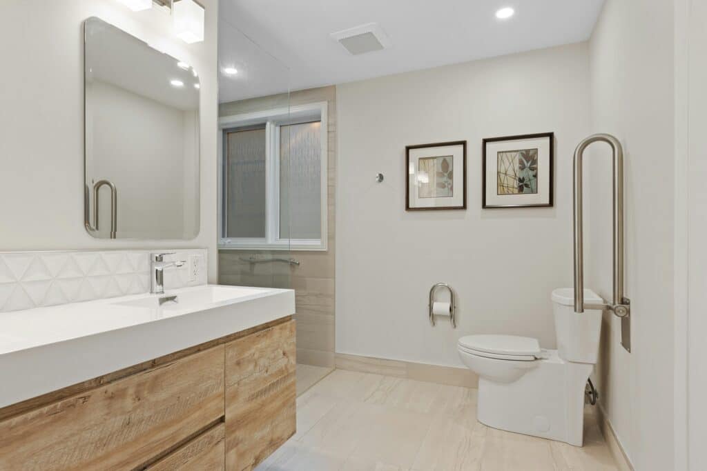 blog image 1 Modern bathroom with wooden vanity, large mirror, toilet, and framed art on beige walls. | Sky Rye Design Modern bathroom with wooden vanity, large mirror, toilet, and framed art on beige walls.