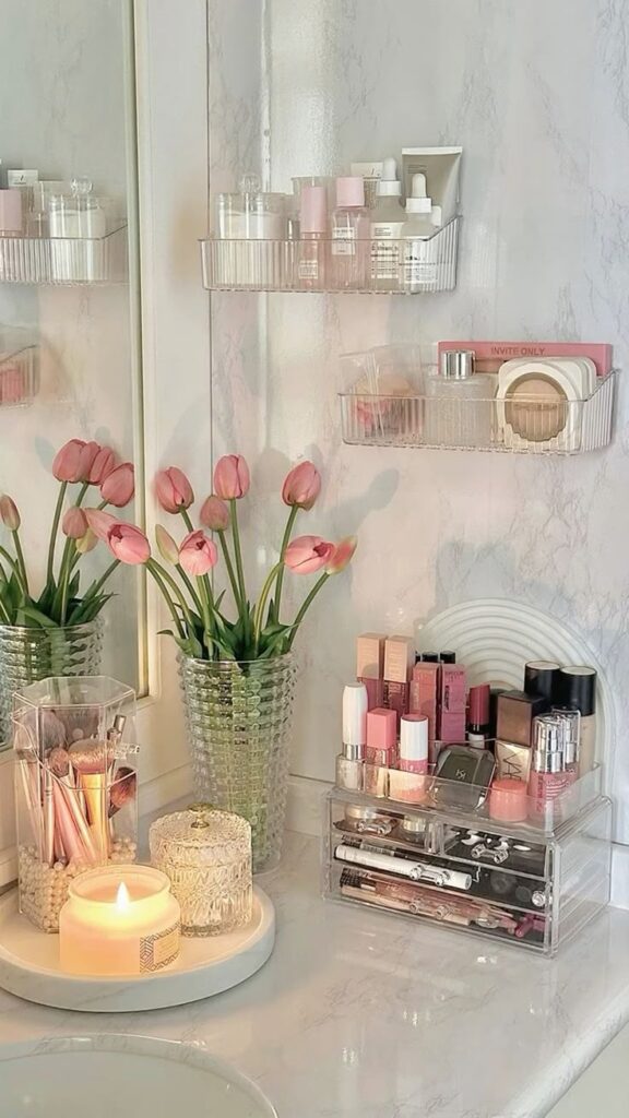 Elegant vanity setup with pink tulips, candles, and organized makeup on a marble countertop.