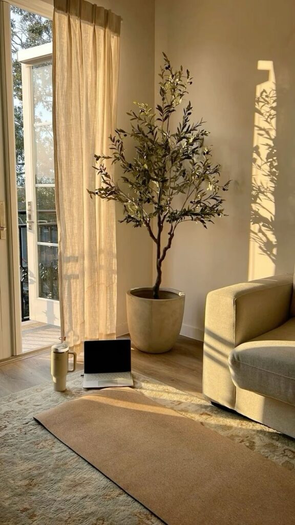 Bright room with yoga mat, laptop, and plant, sunlight streaming through open balcony doors with sheer curtains.
