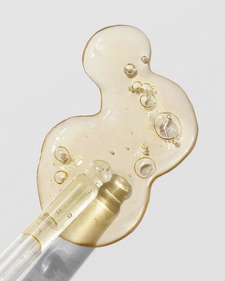 Transparent serum with bubbles and dropper on a light background, highlighting skincare hydration and glow.